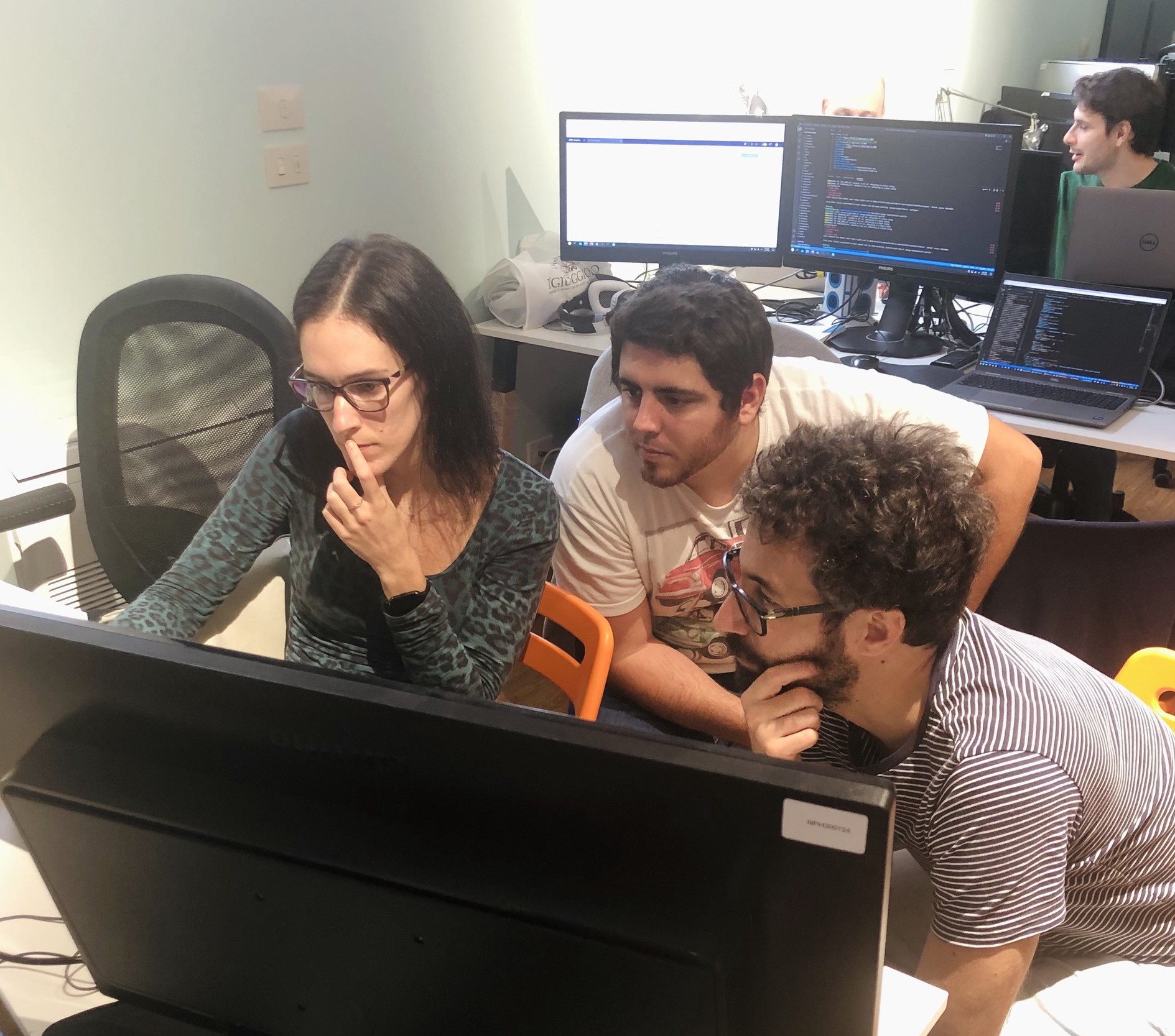 Alcuni membri del team Nephila impegnati in una sessione di pair programming attorno a una scrivania con dei computer.